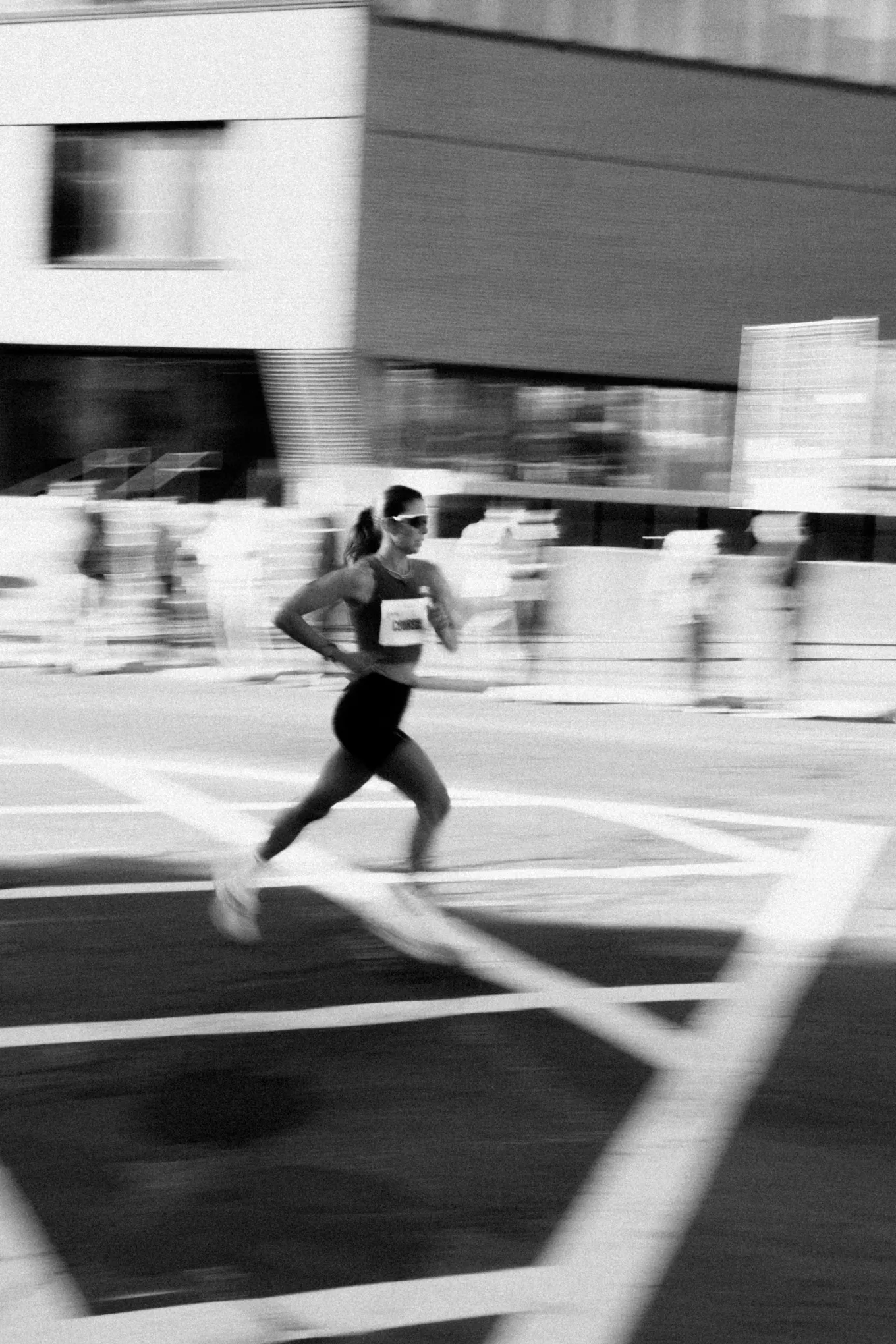 A runner mid-stride during a road race, panned in black and white.